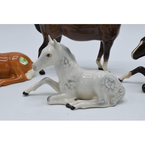 136 - A collection of Beswick horses to include lying foals 915 in grey, brown and palomino colourway toge... 