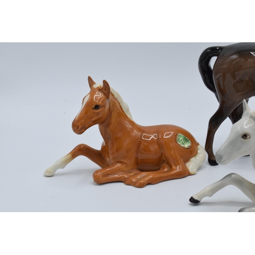 136 - A collection of Beswick horses to include lying foals 915 in grey, brown and palomino colourway toge... 