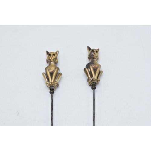 239 - A pair of vintage cast brass hat pins on steel sticks (2). 22cm long.