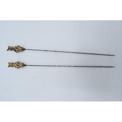 239 - A pair of vintage cast brass hat pins on steel sticks (2). 22cm long.