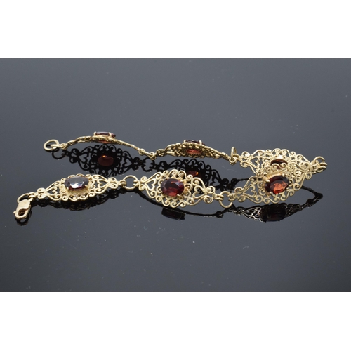 403 - 9ct gold ornate ladies bracelet set with garnets. 8.1 grams. 19.5cm long.