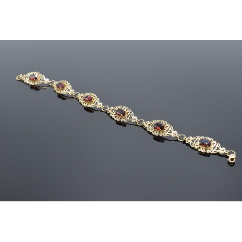 403 - 9ct gold ornate ladies bracelet set with garnets. 8.1 grams. 19.5cm long.