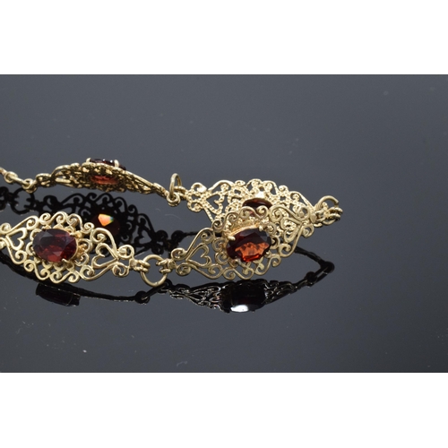 403 - 9ct gold ornate ladies bracelet set with garnets. 8.1 grams. 19.5cm long.