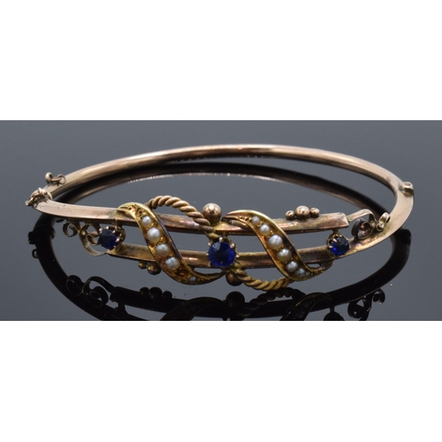 408 - 9ct rose gold ladies bangle set with seed pearls and sapphires (or similar). 6.7 grams. 68mm wide.