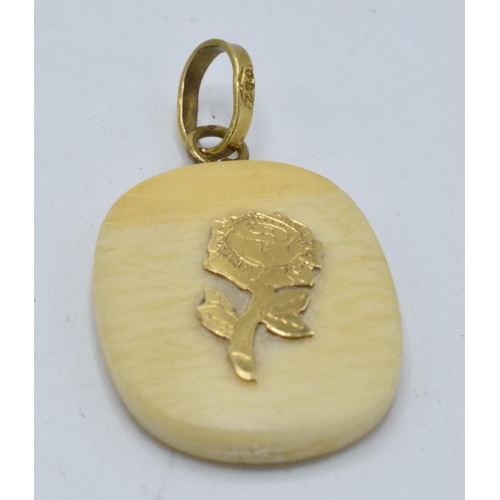 451 - A bone pendant with 18ct gold floral decoration and mount. 22mm tall.