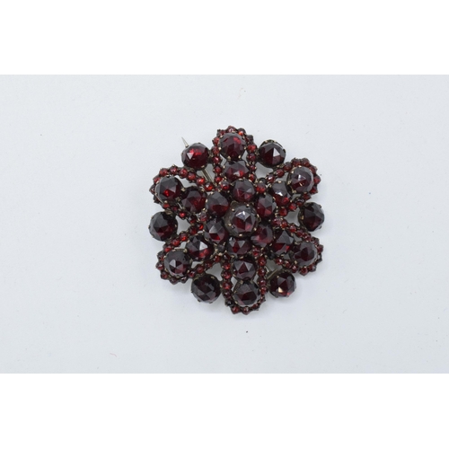 456 - 9ct gold and garnet set brooch, not hallmarked but tested as 9ct gold, 9.9g, 35mm wide.