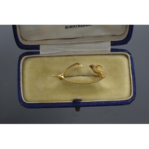 462 - 15ct gold wishbone brooch set single pearl and a standing chick with ruby eye, 2.8g, 33cm wide.