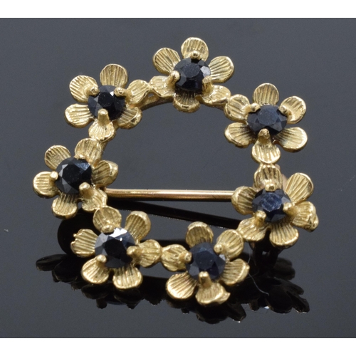 484 - 9ct gold circular brooch set with sapphires in a floral design, 2.3 grams.