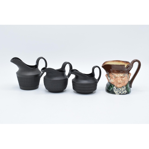 84 - A trio of 19th century black basalt cream jugs with engineered decoration to include one of tapering... 