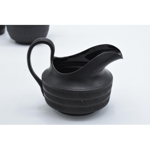 84 - A trio of 19th century black basalt cream jugs with engineered decoration to include one of tapering... 