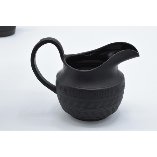 84 - A trio of 19th century black basalt cream jugs with engineered decoration to include one of tapering... 