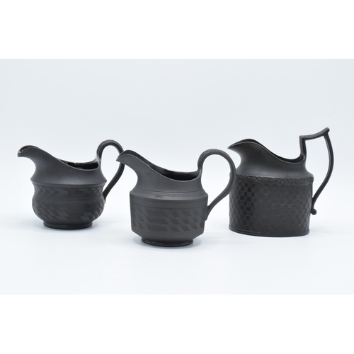 85 - A trio of 19th century black basalt jugs all with chequered engineered patterns (3). 12cm tallest.