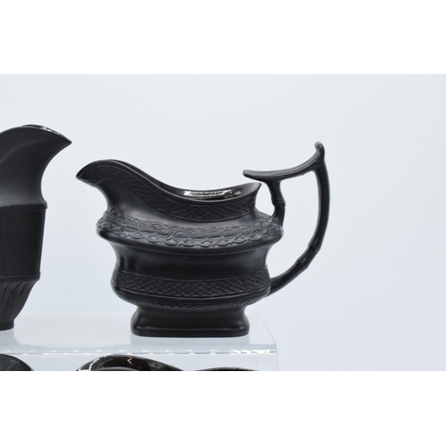 96 - A collection of black basalt milk jugs, circa 1800-1810, to include an oval example sprigged with 'H... 