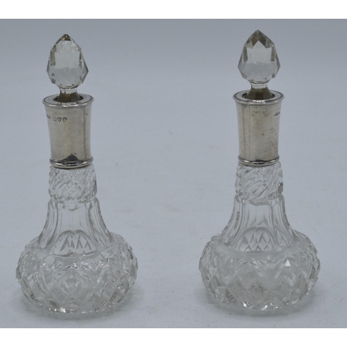 375C - A pair of silver-rimmed glass scent bottles, Chester 1912. 12cm tall.