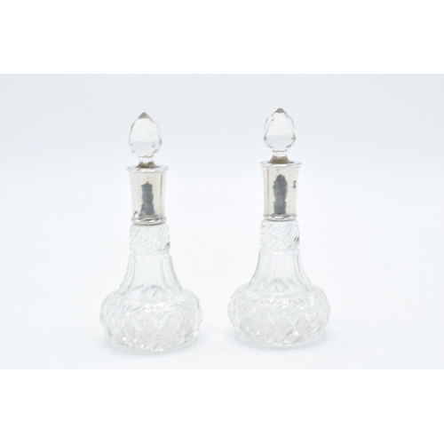 375C - A pair of silver-rimmed glass scent bottles, Chester 1912. 12cm tall.