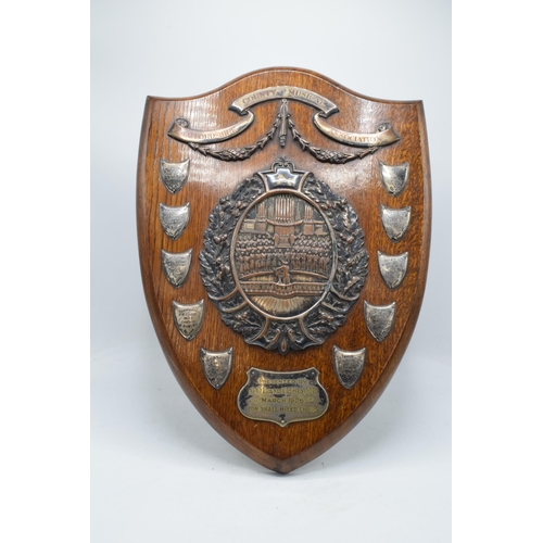 245 - A wooden presentation shield with hallmarked silver name shields and a silver plate central relief a... 