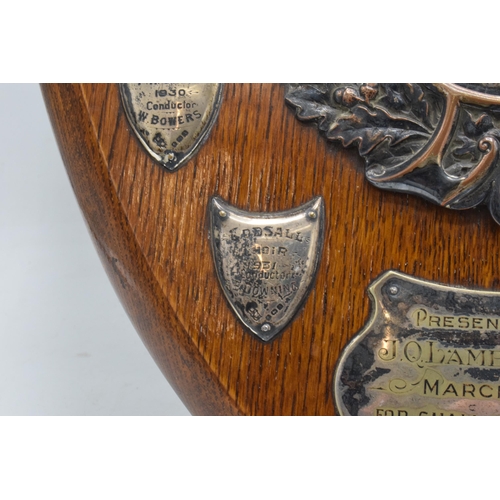 245 - A wooden presentation shield with hallmarked silver name shields and a silver plate central relief a... 