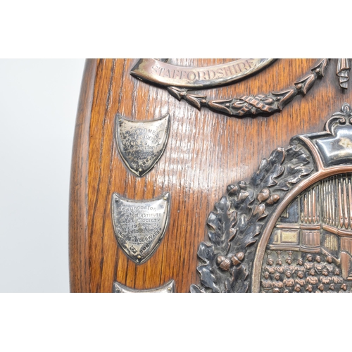 245 - A wooden presentation shield with hallmarked silver name shields and a silver plate central relief a... 