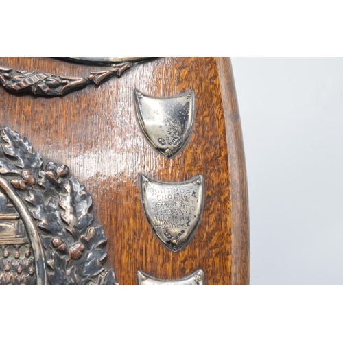 245 - A wooden presentation shield with hallmarked silver name shields and a silver plate central relief a... 