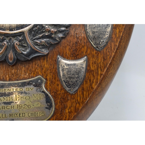 245 - A wooden presentation shield with hallmarked silver name shields and a silver plate central relief a... 