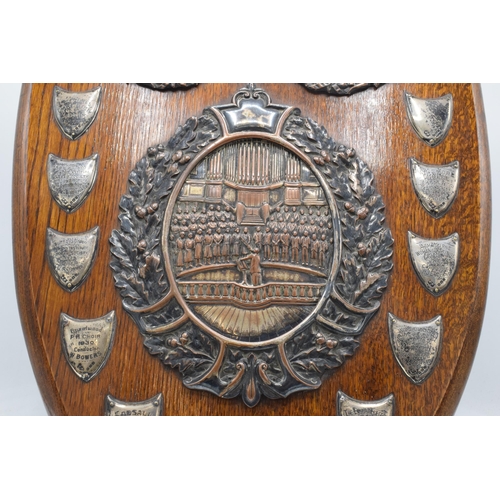 245 - A wooden presentation shield with hallmarked silver name shields and a silver plate central relief a... 