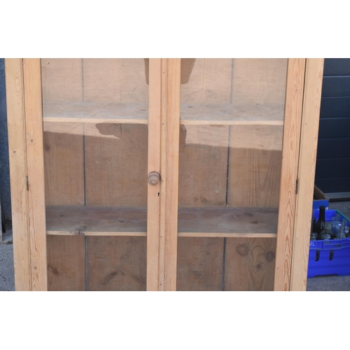 274 - An early 20th century tall pine display cabinet with glazed doors, 106x35x139cm tall.