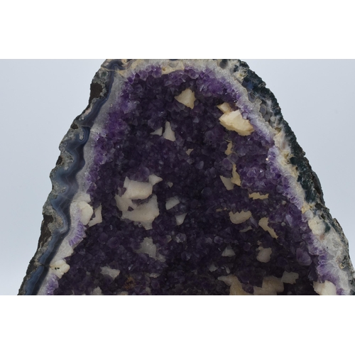 294 - A geological rock specimen of an amethyst geode, 38cm wide, 31cm tall.