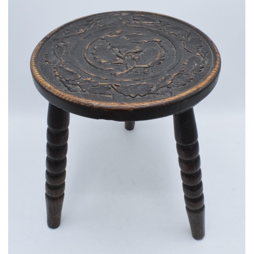 304 - 19th century traditional carved oak milking stool on three turned legs, 31cm tall.