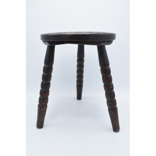 304 - 19th century traditional carved oak milking stool on three turned legs, 31cm tall.