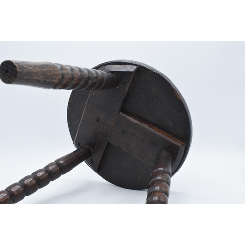 304 - 19th century traditional carved oak milking stool on three turned legs, 31cm tall.