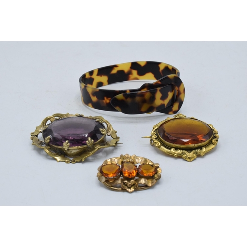 221L - A trio of pinch-back style stone set brooches together with a faux tortoiseshell bangle (4).