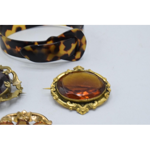 221L - A trio of pinch-back style stone set brooches together with a faux tortoiseshell bangle (4).