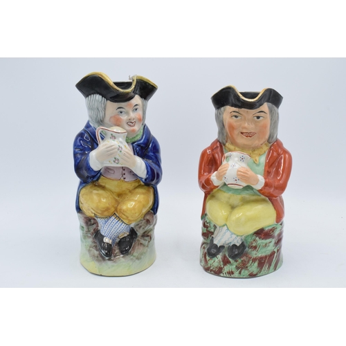 175 - A pair of late 19th century Staffordshire Toby jugs of similar form with each gent having crossed le... 