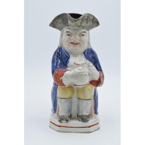 176 - An early 19th century Staffordshire Toby jug of a man in a tricorn hat holding a jug with floral spr... 