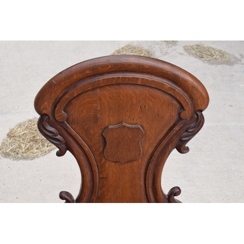 375 - A pair of Victorian oak carved shaped back hall chairs with raised shell motif (2), 86cm tall.