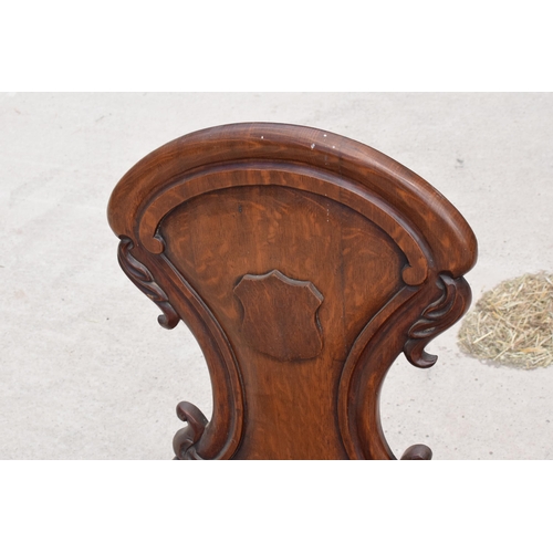 375 - A pair of Victorian oak carved shaped back hall chairs with raised shell motif (2), 86cm tall.