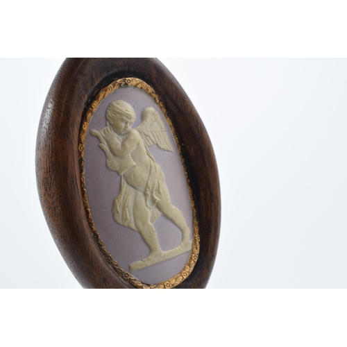 77 - A 19th century lilac jasperware oval cameo of a cherub with domed shaped with gilt floral edge in wo... 