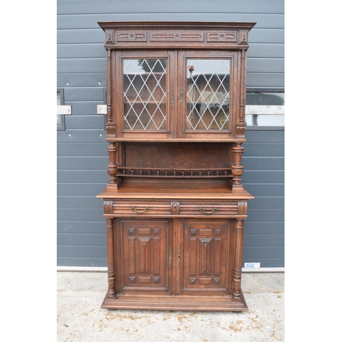395A - An early 20th century wooden kitchen dresser with glazed upper doors and carved decoration. 218cm ta... 