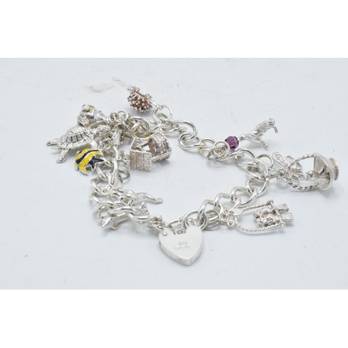 366 - Silver charm bracelet with array of charms to include basket, turtle and others, 36.7 grams.