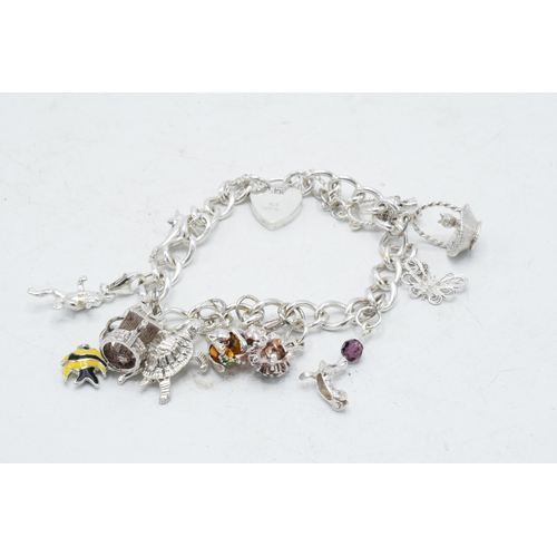 366 - Silver charm bracelet with array of charms to include basket, turtle and others, 36.7 grams.