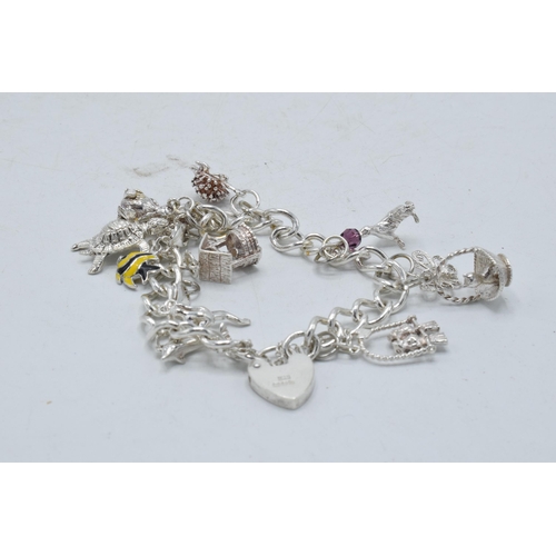 366 - Silver charm bracelet with array of charms to include basket, turtle and others, 36.7 grams.