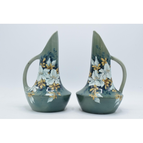 27 - A pair of 19th century floral hand-painted ewers, 24cm tall.