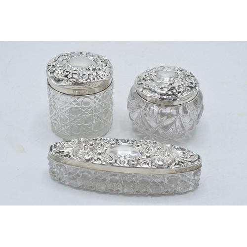 205G - A trio of Edwardian hallmarked silver lidded glass jars to include Chester 1911, 1905 and Birm 1902 ... 