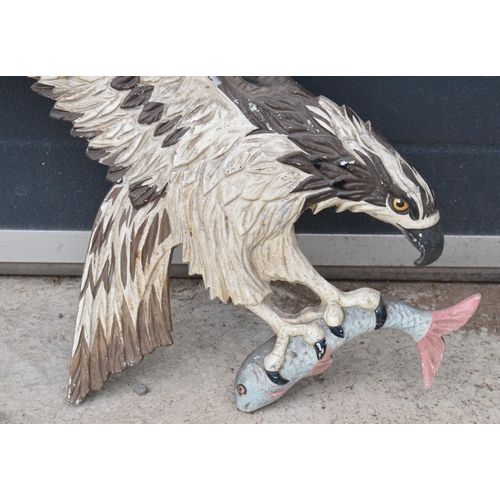 248 - A cast metal wall plaque of an eagle carrying a fish, 67cm tall.