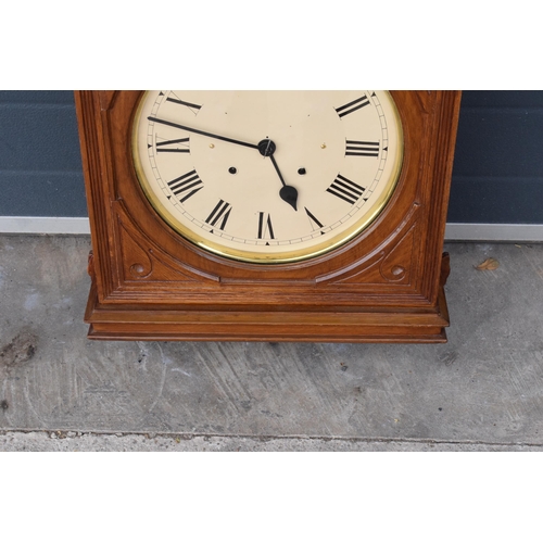 312 - 20th century wooden cased wall clock, in the style of Seth Thomas, with key and pendulum. 58cm long.