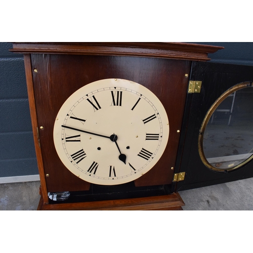 312 - 20th century wooden cased wall clock, in the style of Seth Thomas, with key and pendulum. 58cm long.