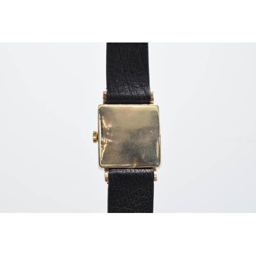 125 - 9ct gold Garrard wristwatch on black leather strap, heavy case, does wind and tick though does need ... 