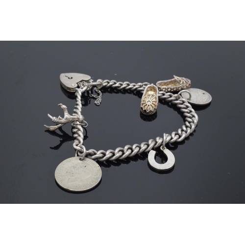 170 - Silver charm bracelet set with a silver coin and other charms such as shoes etc, 25.7 grams.