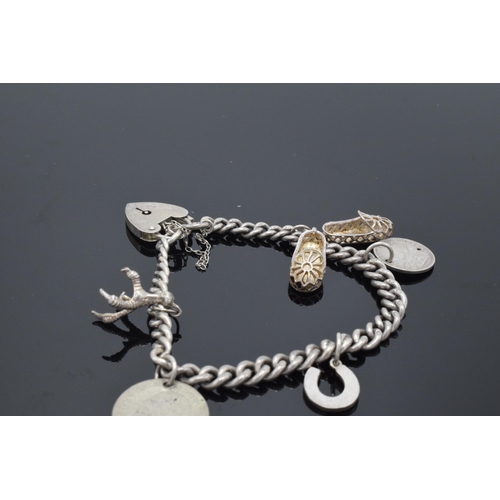 170 - Silver charm bracelet set with a silver coin and other charms such as shoes etc, 25.7 grams.