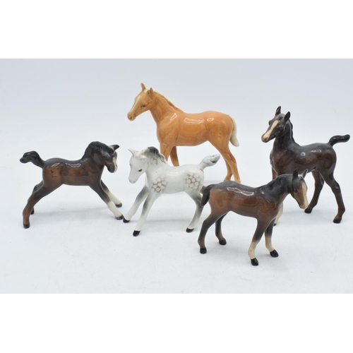 60H - A collection of Beswick foals to include a palomino example, a grey foal and 3 in brown colourways i... 